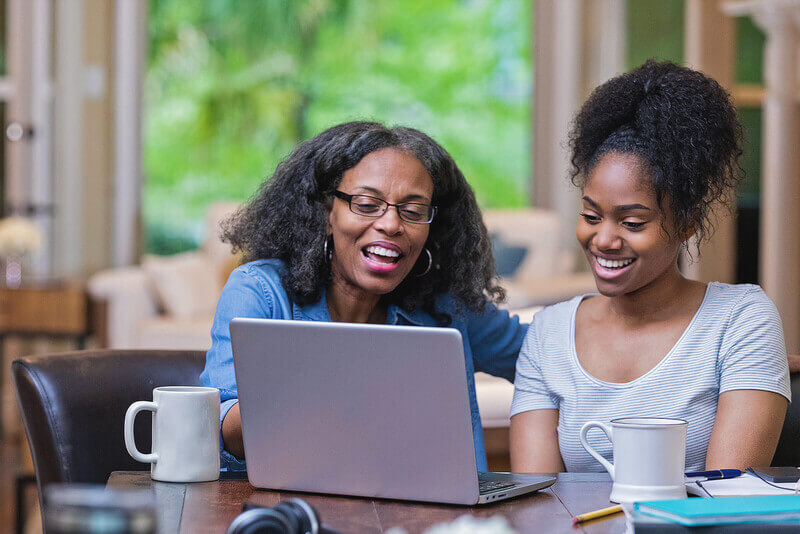 a mother and daughter look at a list of schools with legacy admissions on a laptop