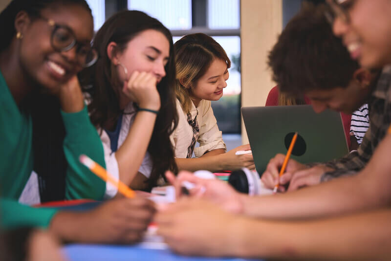 a group of students pictured from the side doing school work