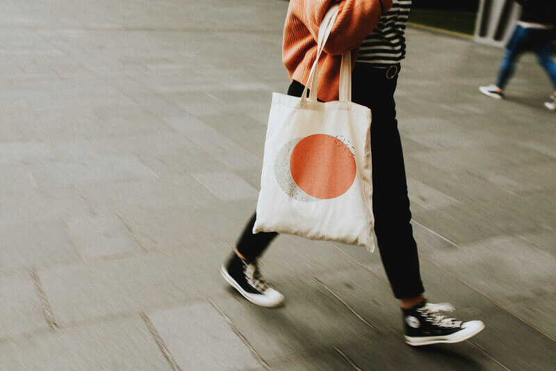 a student walks through a college fair carrying a tote bag