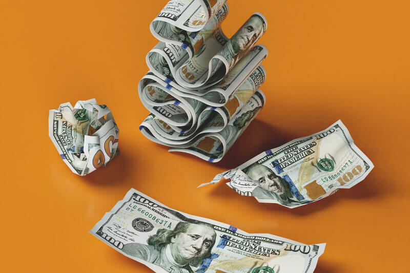 dollar bills stacked and crumpled on an orange background
