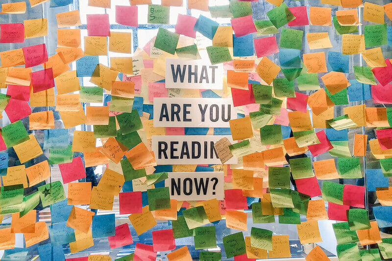 A window covered in post-it notes with the question, "what are you reading now?", in the center.