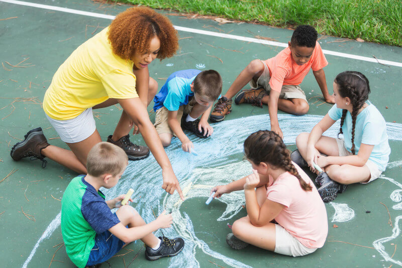a high school student supervises kids on a playground