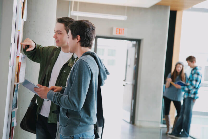 two students look at a bulletin board to see volunteer opportunities