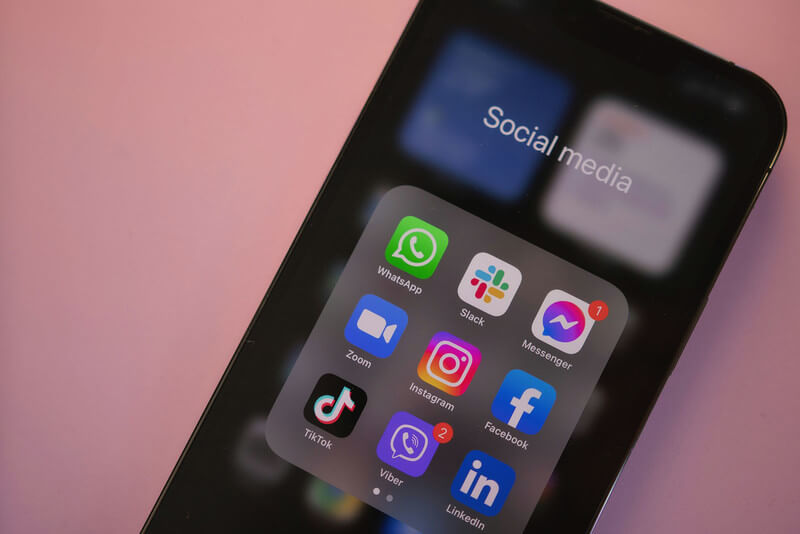 A close up of a smartphone displaying social media icons of whats app, slack, facebook messenger, facetime, instagram, facebook, tiktok, viber and linked in.