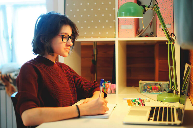 a female student writing an essay at a desk