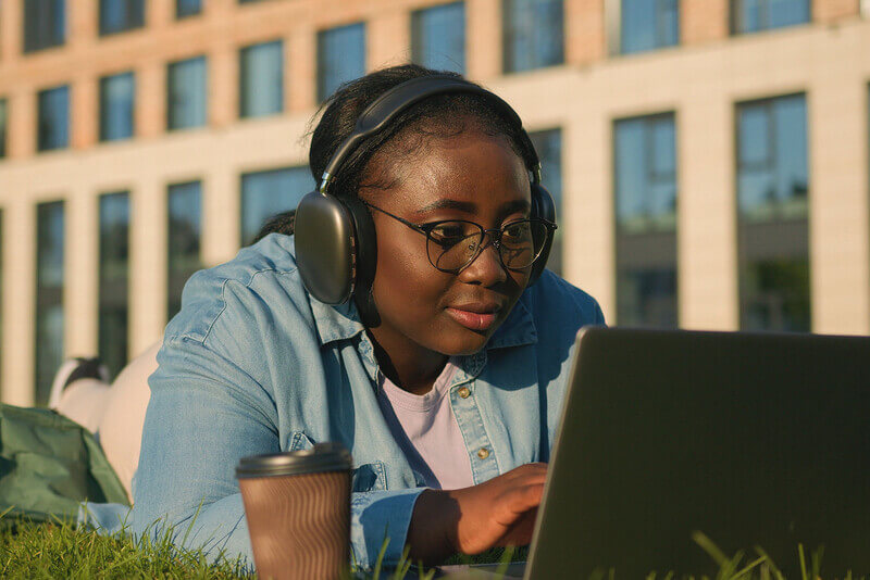 a student writes a letter on her laptop wearing ear phones