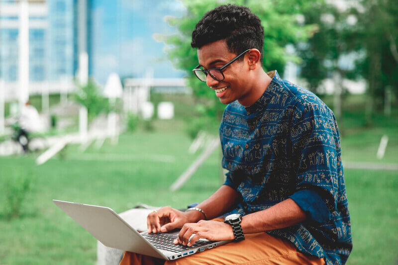 Student sitting outside looking at a laptop.