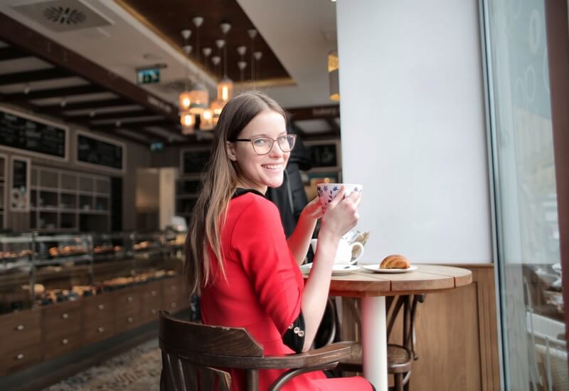 a female student in a red dress drinks tea in a coffee shop
