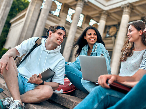 a small group of students sits on the steps of a college campus